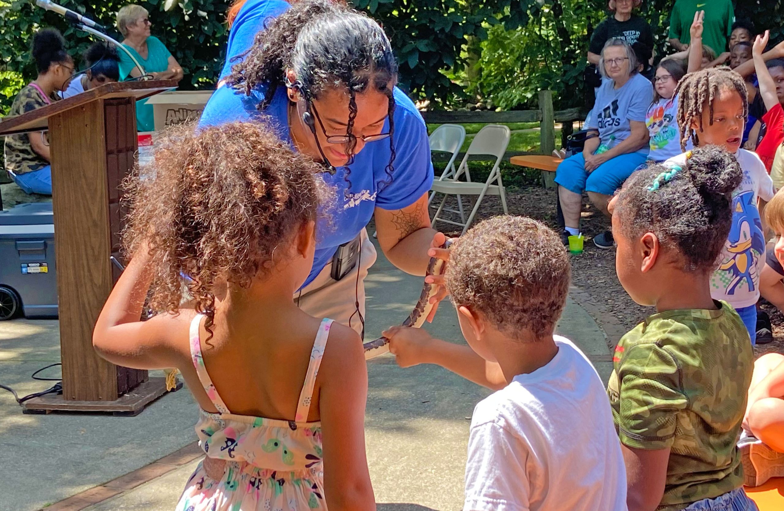Children touching a snake held by a zookeeper