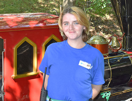 Smiling zoo employee standing in front of the zoo train